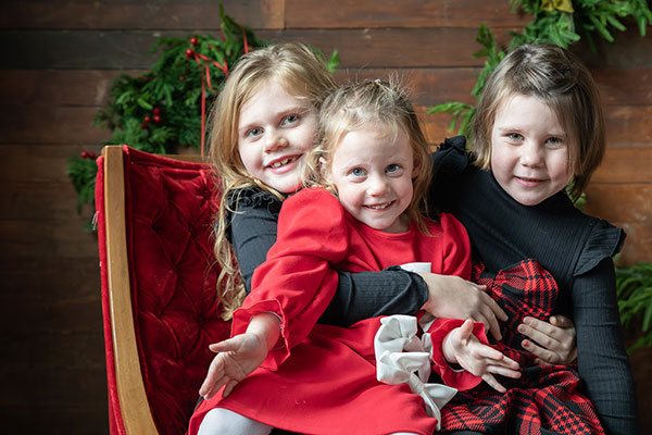 three girls smiling at camera, in Christmas outfits