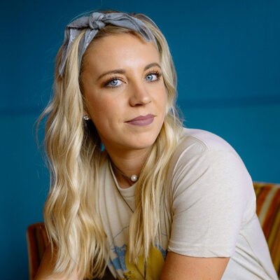 woman with long blonde hair looks at the camera with bow on her head